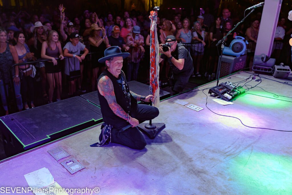 a male performer kneeling on the stage with the audience behind him