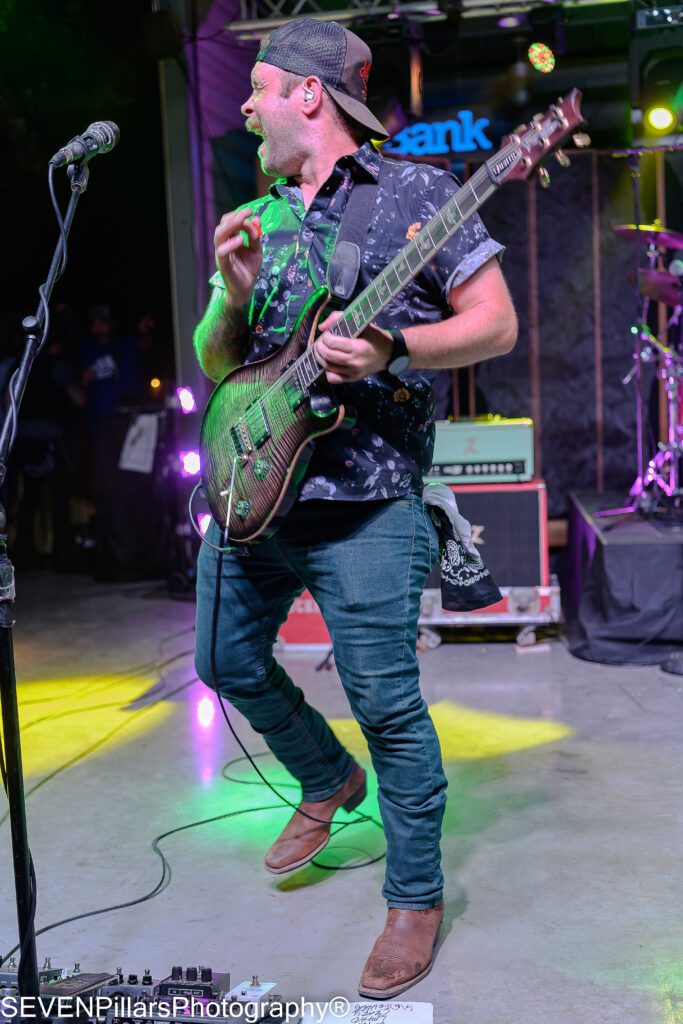 Christopher Skiles playing his guitar near a microphone stand