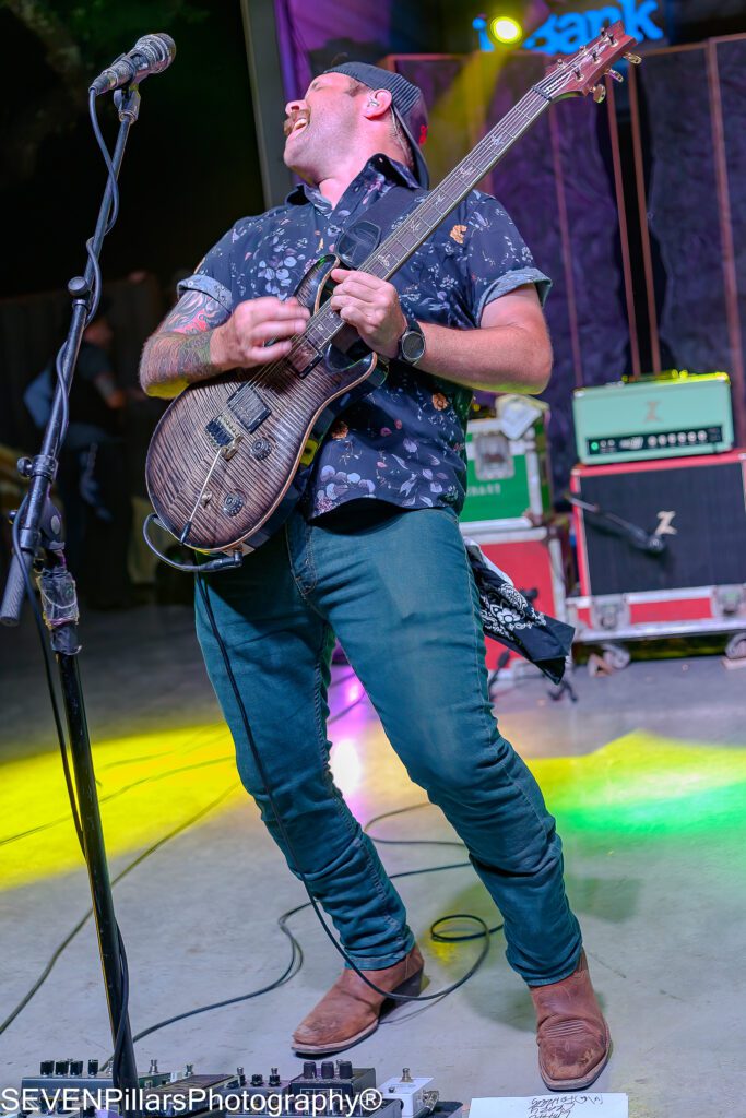 Christopher Skiles playing his guitar while leaning