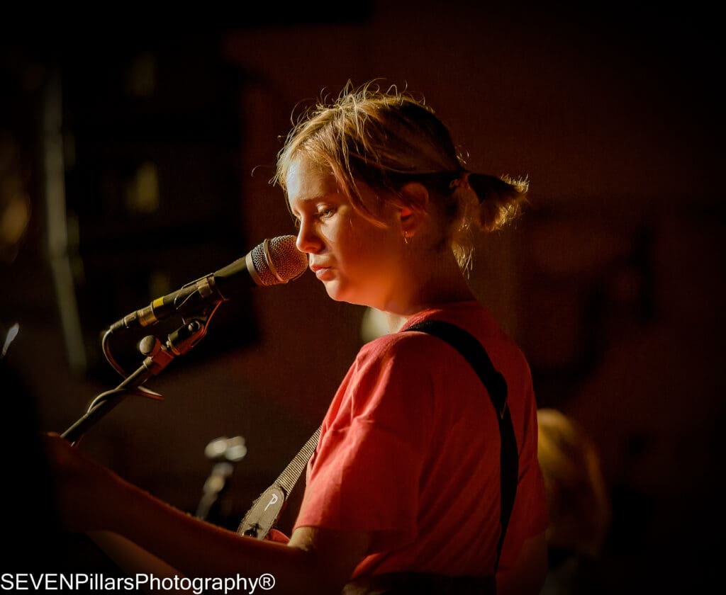 a female bassist in front of a microphone stand