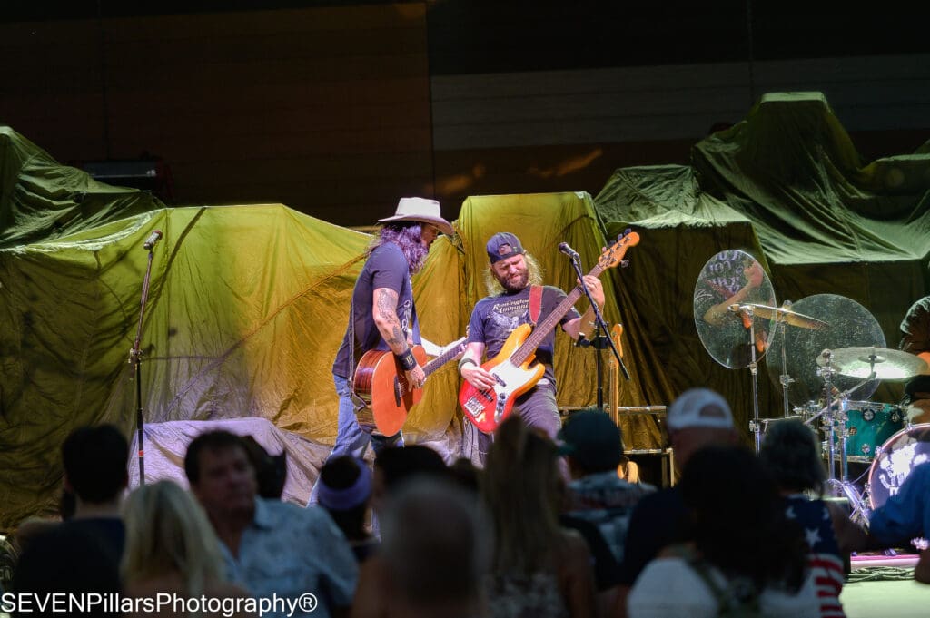 two members of a band performing on the stage in front of music fans