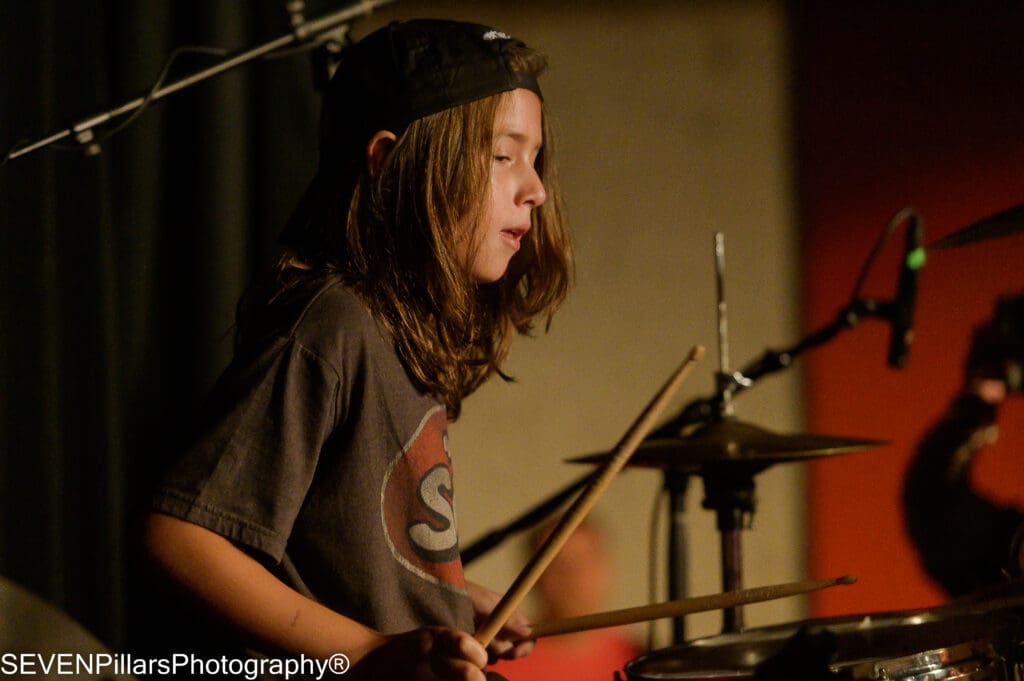 a long-haired teenage boy drummer