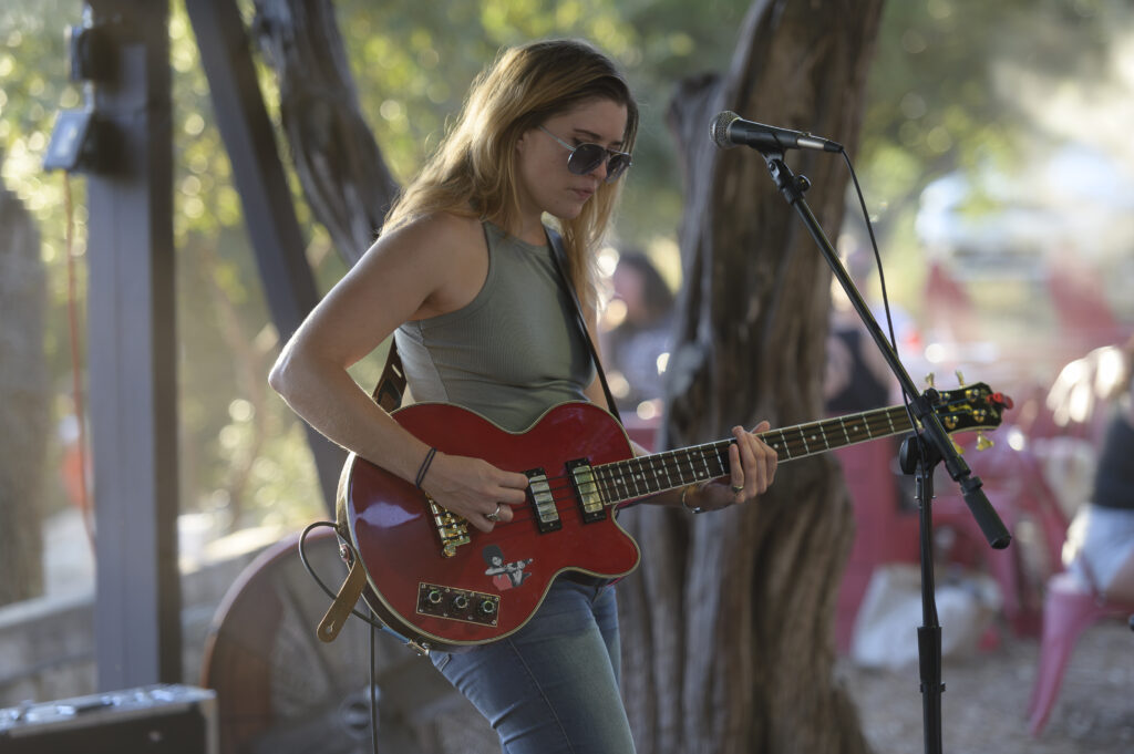 A woman playing a red guitar in front of a microphone.