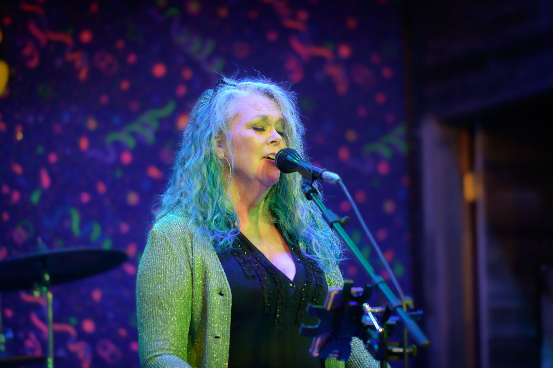 A woman with blue hair singing into a microphone.