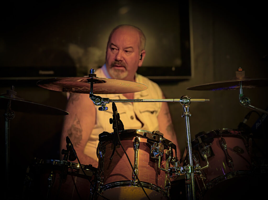 A man playing drums in a dark room.