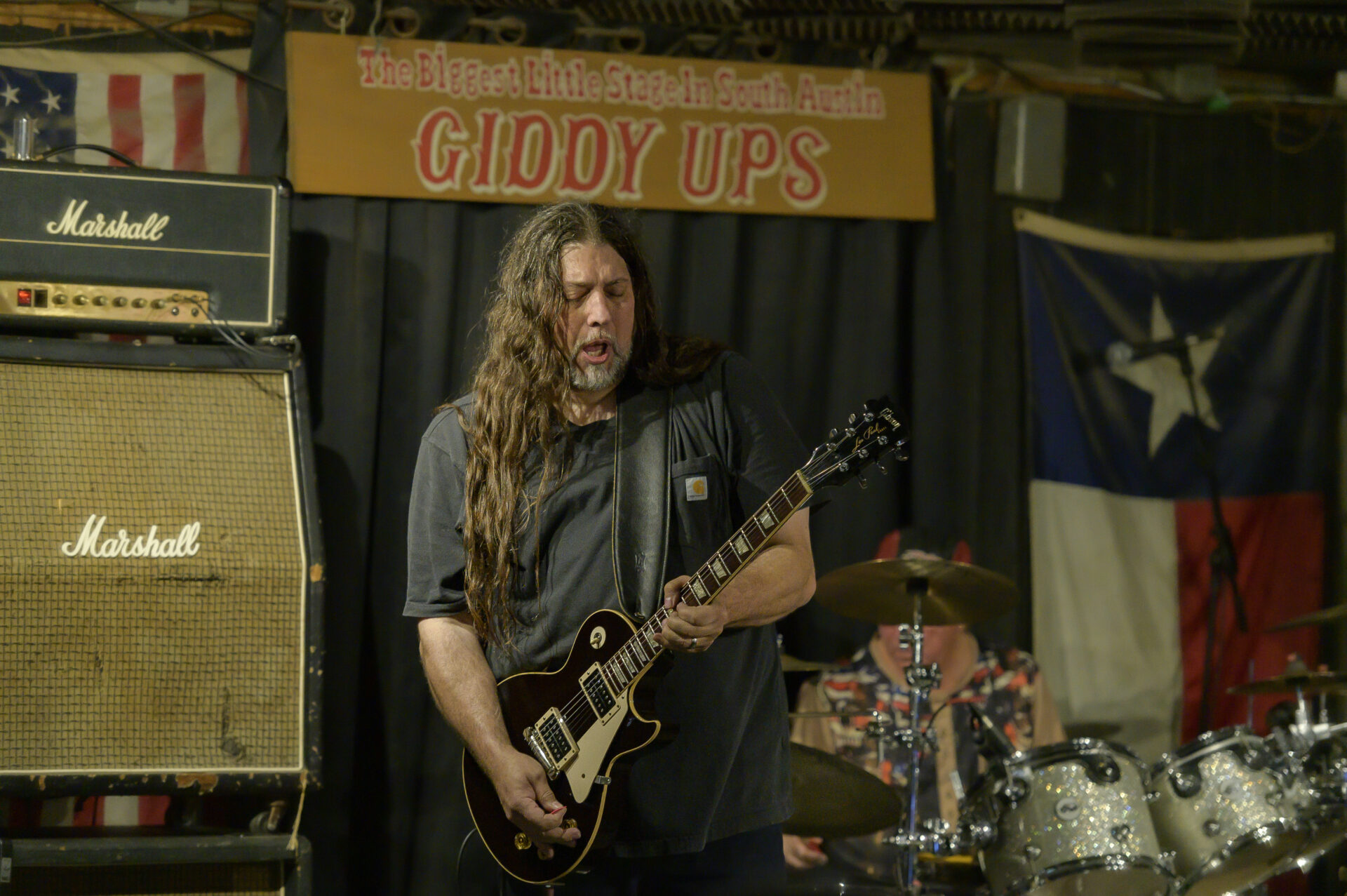 A man playing guitar in front of an american flag.