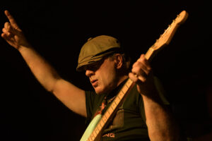 A man in a hat playing an electric guitar.