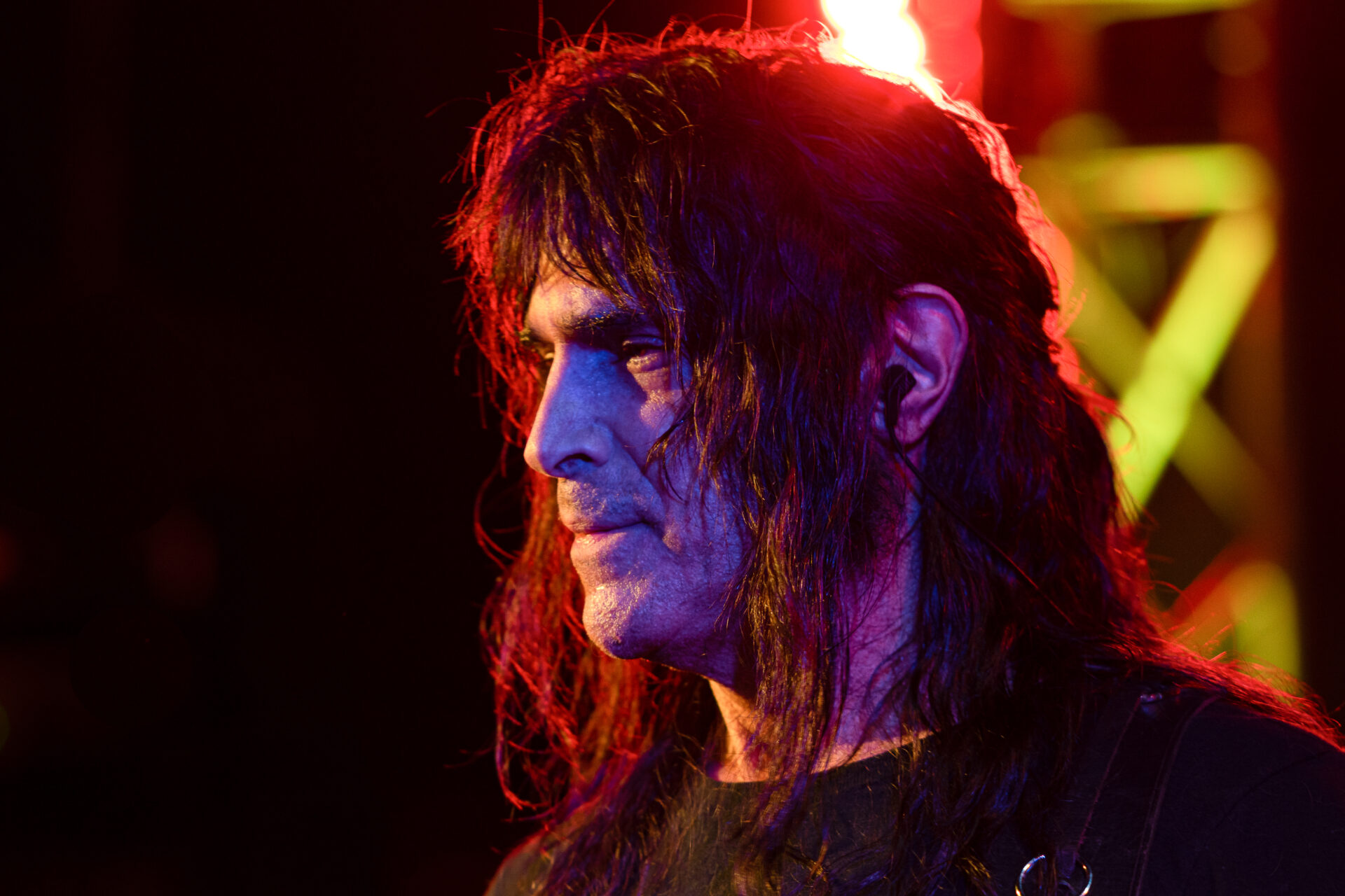 A man with long hair standing in front of a stage.