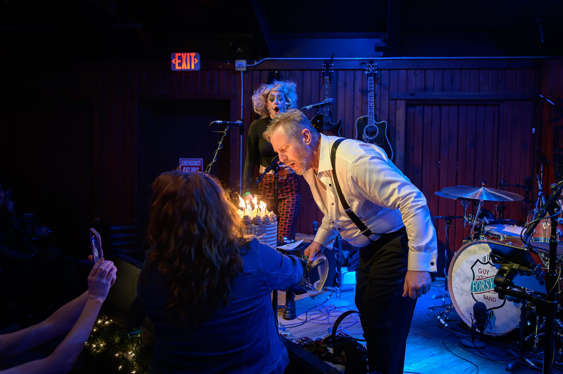 A man is holding a candle on stage in front of a group of people.