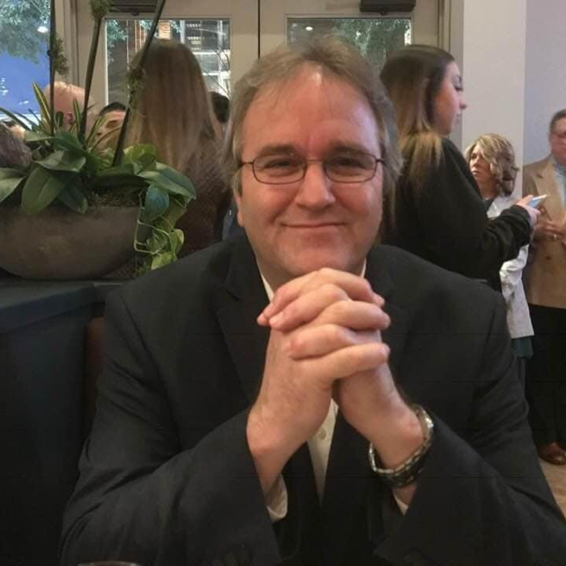 A man sitting at a table with a glass of wine.