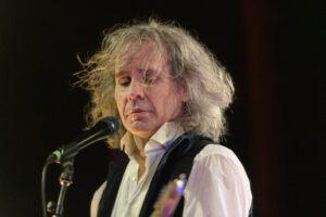 A man with long hair singing into a microphone.