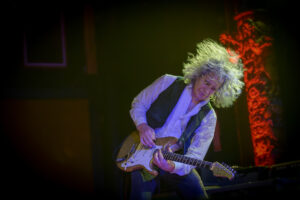 A man playing an electric guitar on stage.