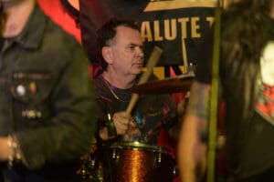 A man is playing drums in front of a crowd.